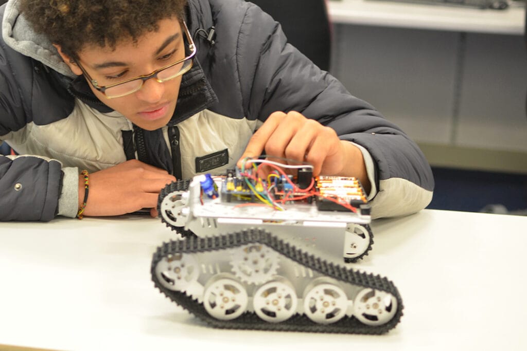 A student looks closely at the electronics of a small gadget.