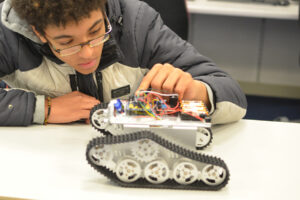 A student looks closely at the electronics of a small gadget.