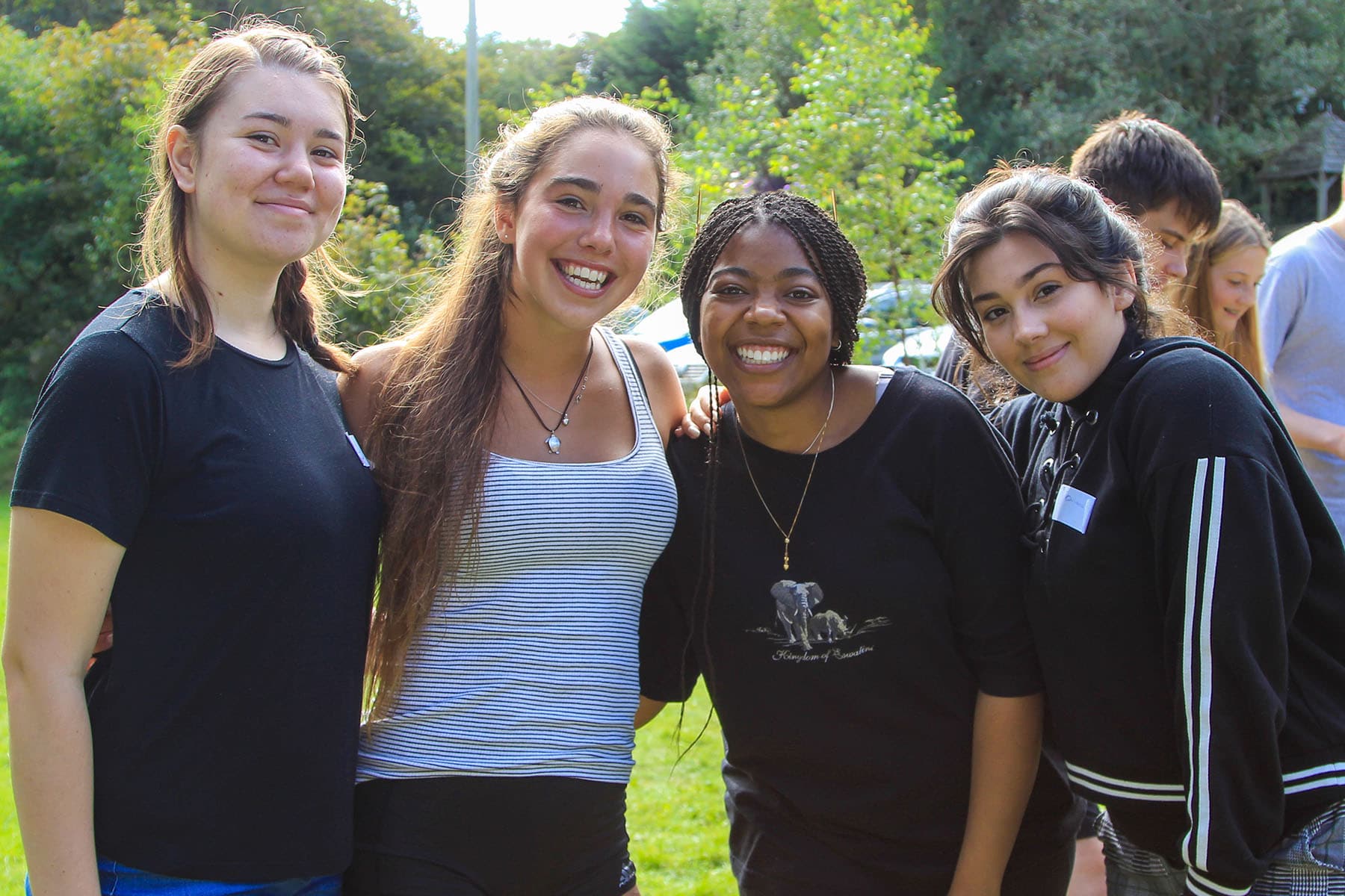 Students from the IB diploma put their arms around each other and smile at the camera.