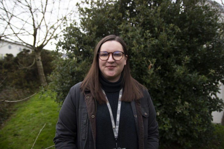 Emily stood outside in front of foliage