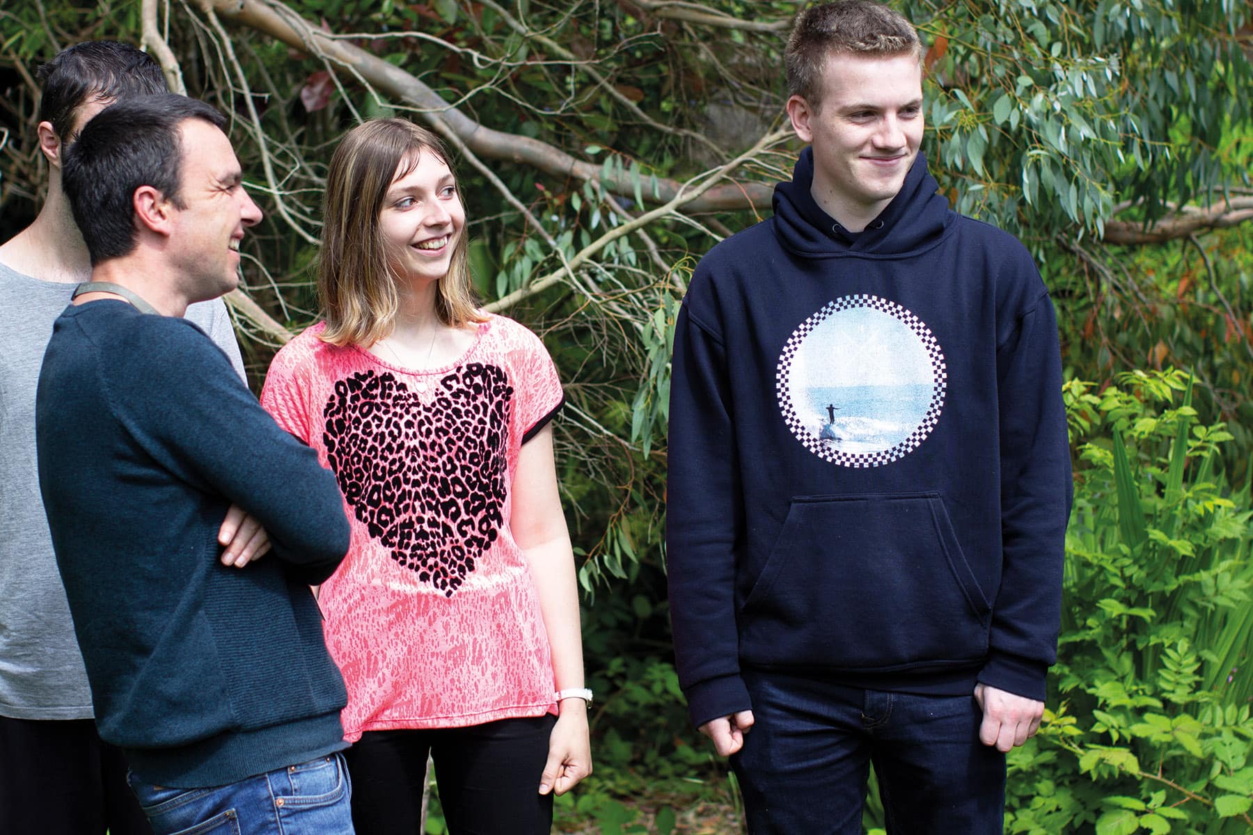 Three students and a member of staff stand outside, laughing and smiling.