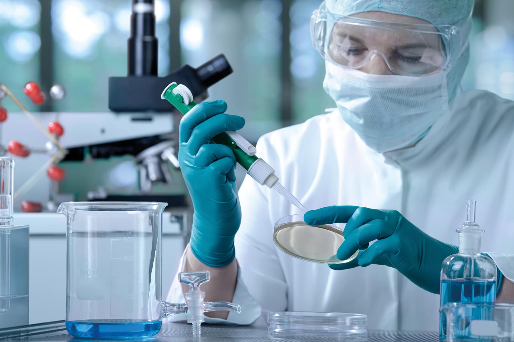 A scientist wearing protective clothing works within a labratory setting.