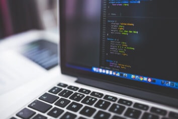 A stock photo of a laptop with coding on screen.