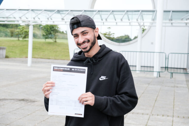 Abdul holding his results outside the Fal building