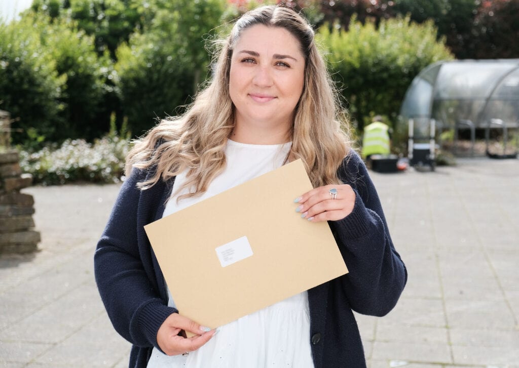 Amy Stood outide holding her results envelope