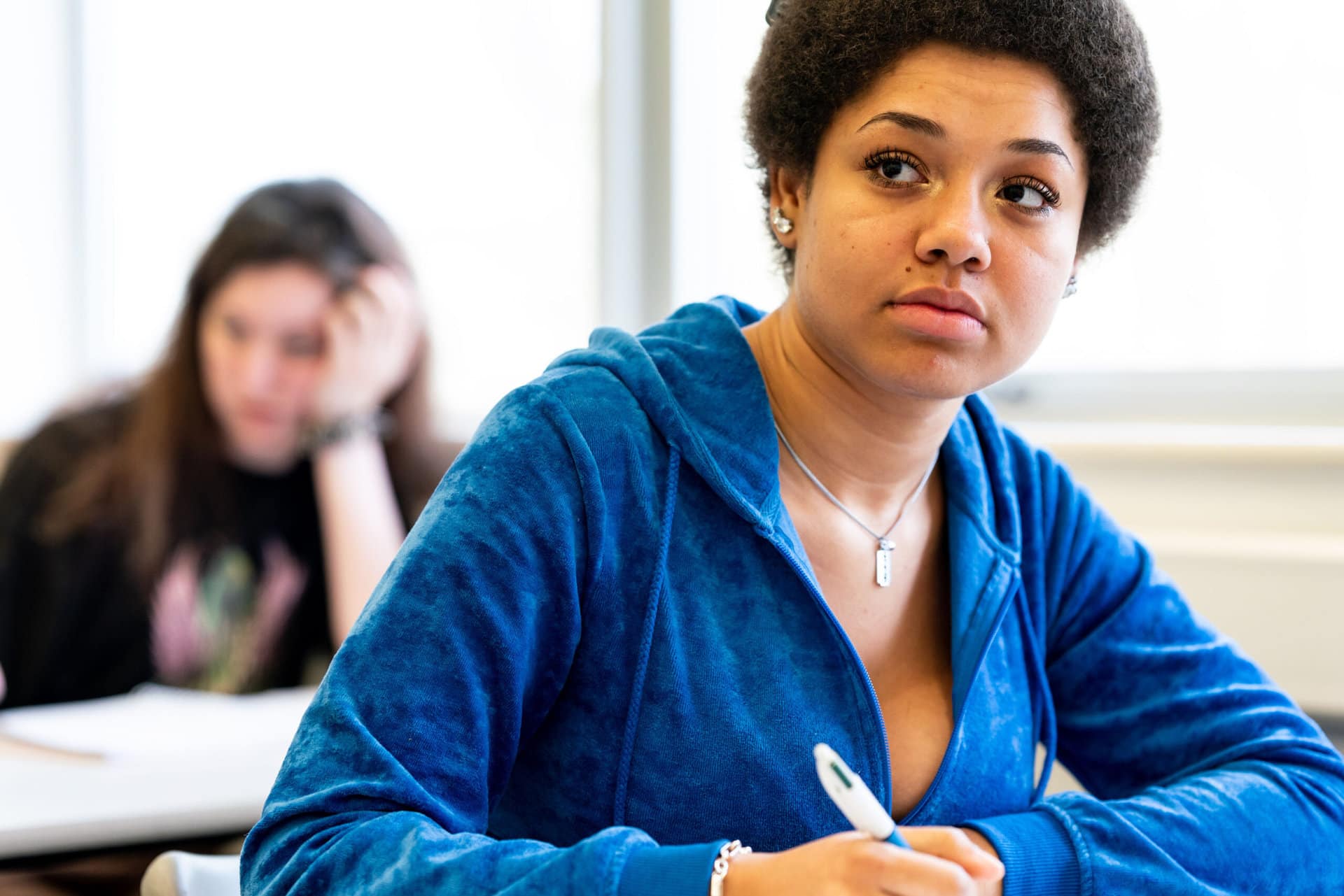 A humanities and social sciences student sits at a desk with pen and paper.