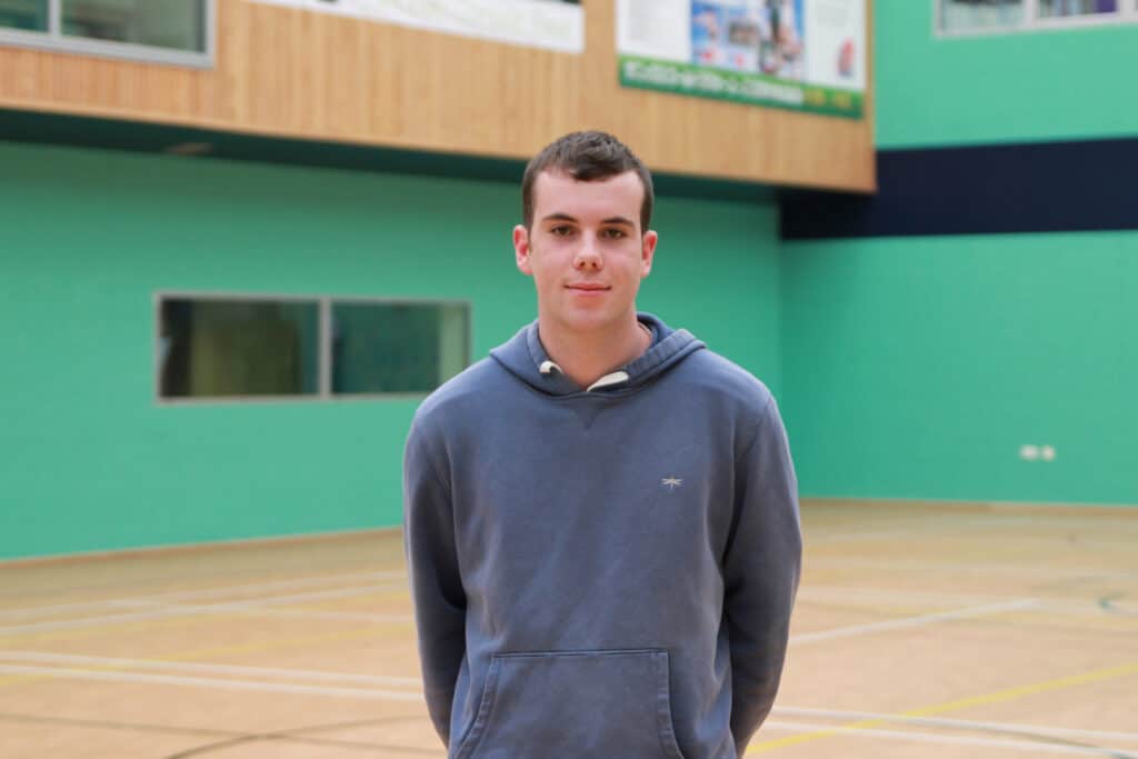 Callum is standing in the College's sports hall