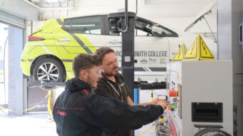 A tutor helps a student with state-of-the-art electric vehicle equipment.