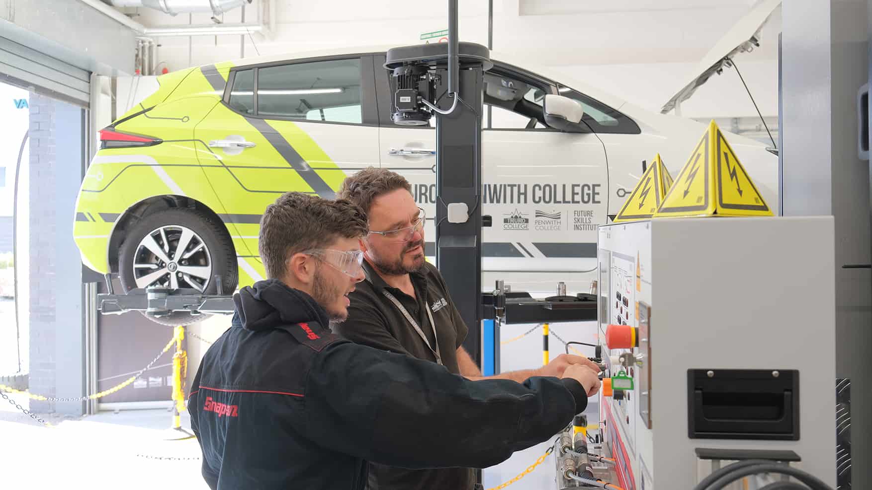 A tutor helps a student with state-of-the-art electric vehicle equipment.