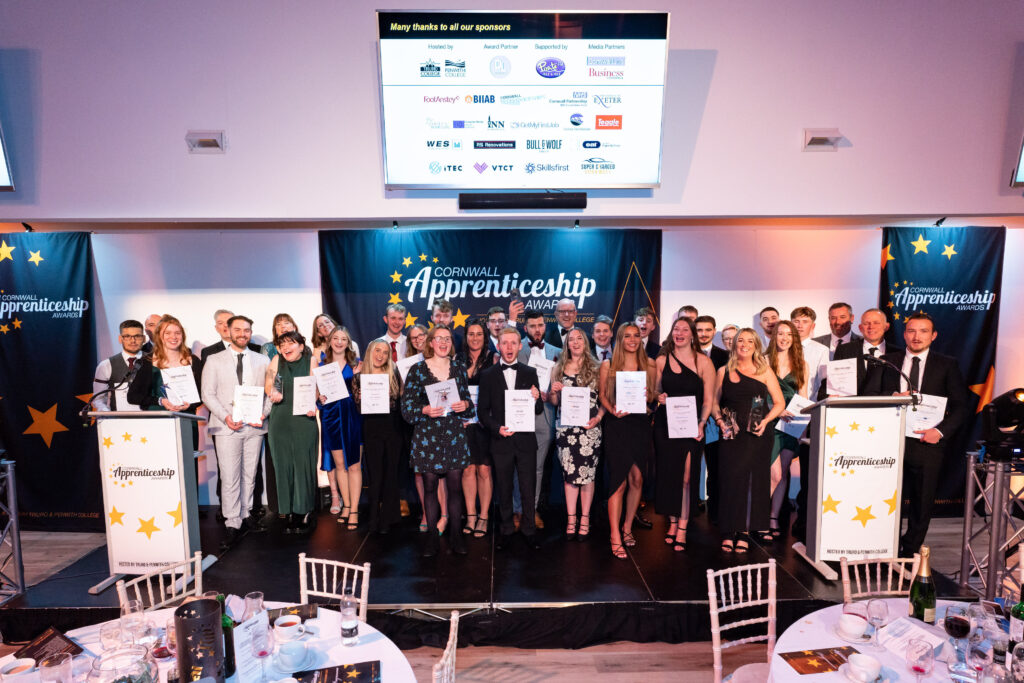 Dressed in black tie and cocktail dresses, the group of almost 40 winners and highly commended nominees at the 2022 Cornwall Apprenticeship Awards stand on stage with their awards and certificates for publicity photos.