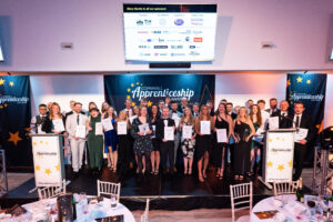 Dressed in black tie and cocktail dresses, the group of almost 40 winners and highly commended nominees at the 2022 Cornwall Apprenticeship Awards stand on stage with their awards and certificates for publicity photos.