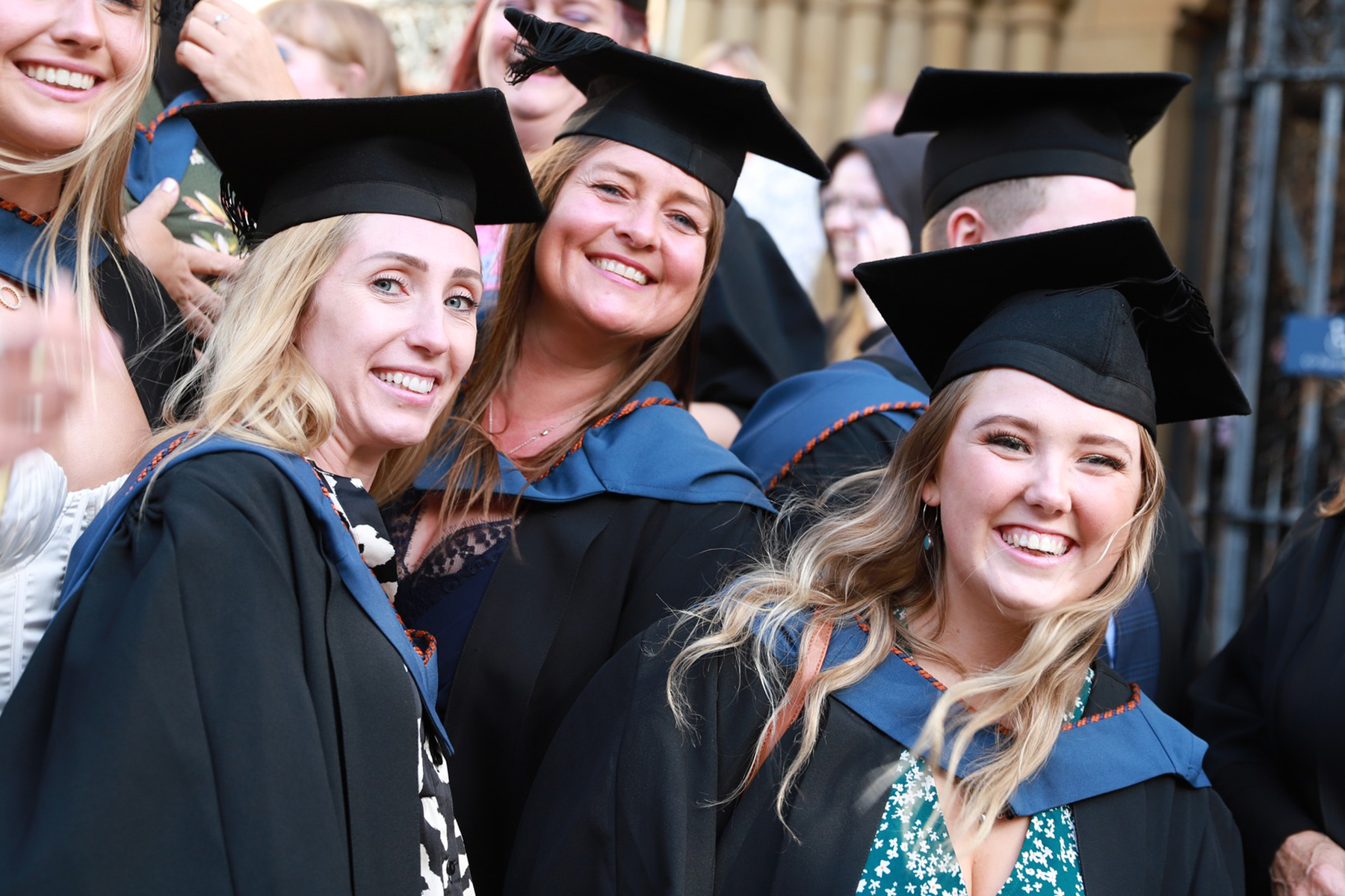 University Centre Truro and Penwith graduates smiling and celebrating in their caps and gowns.