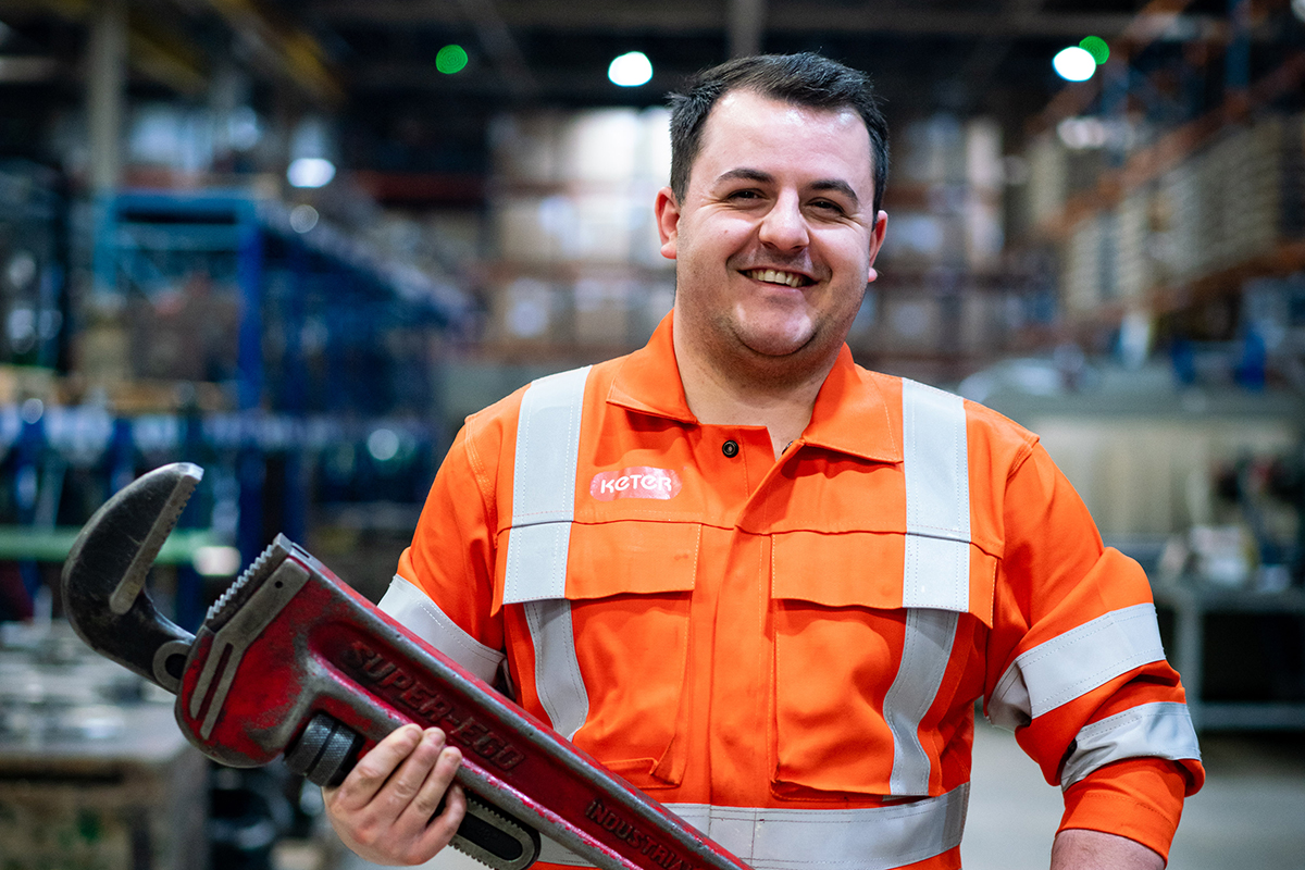 An engineering apprentice in hi-vis uniform in a workshop setting.