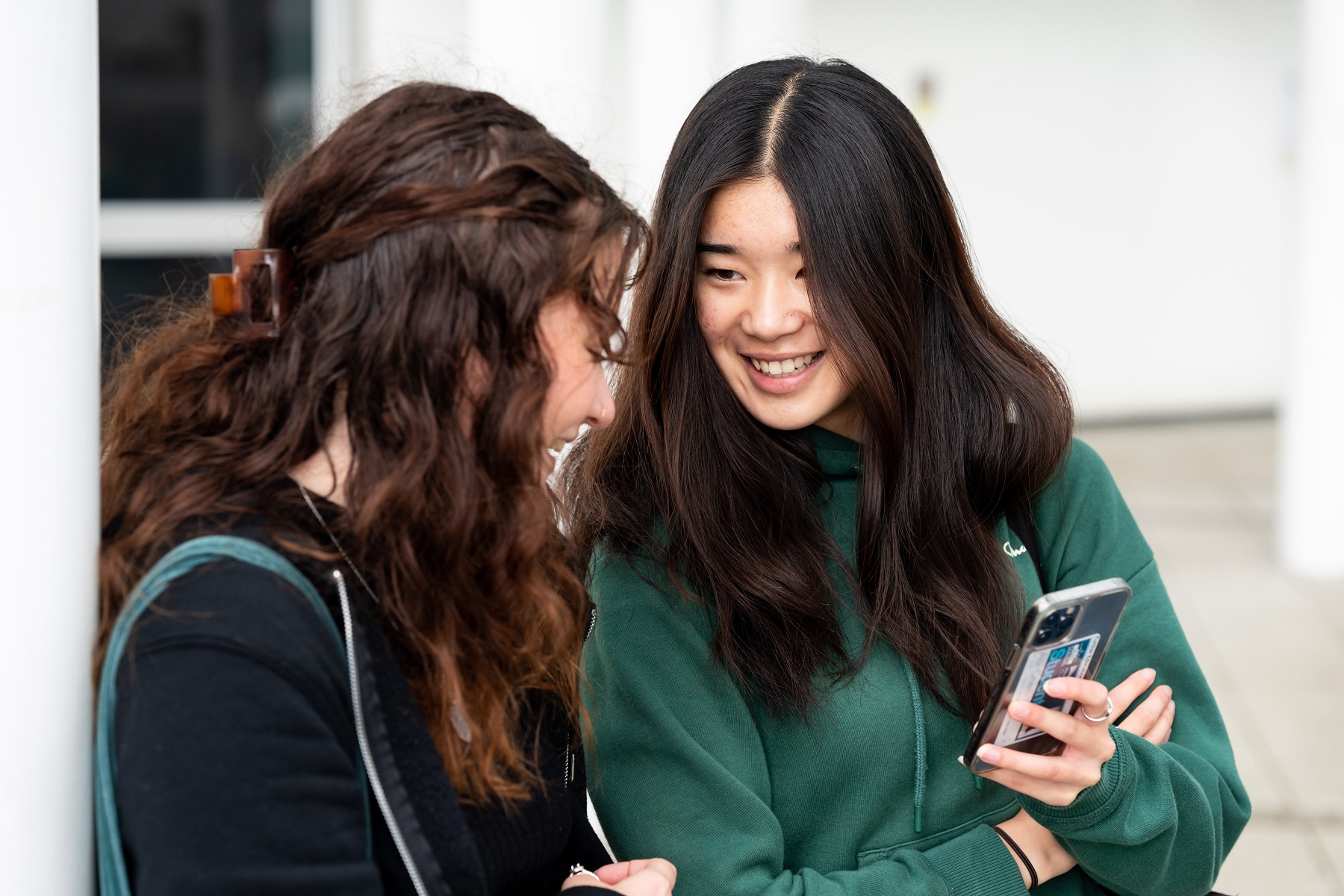 General FE TC 0042 Two students look at a mobile phone that is being held in one of the students' hand.