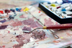 A close-up image of a winsor and newton spatula on a plate with lots of thick paint.