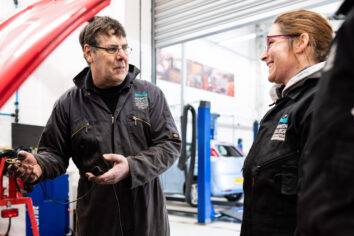 Automotive PC 0007 Two members of staff from the Automotive department are chatting and smiling whilst working under the bonnet of a car.