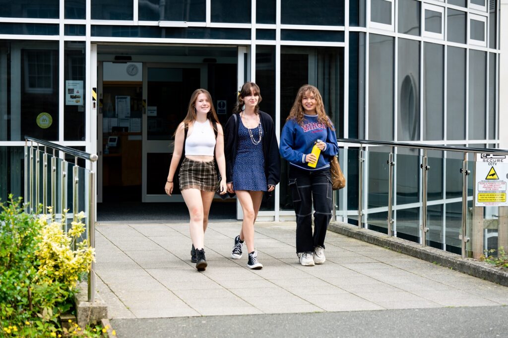 An image of three students walking out of a college building.
