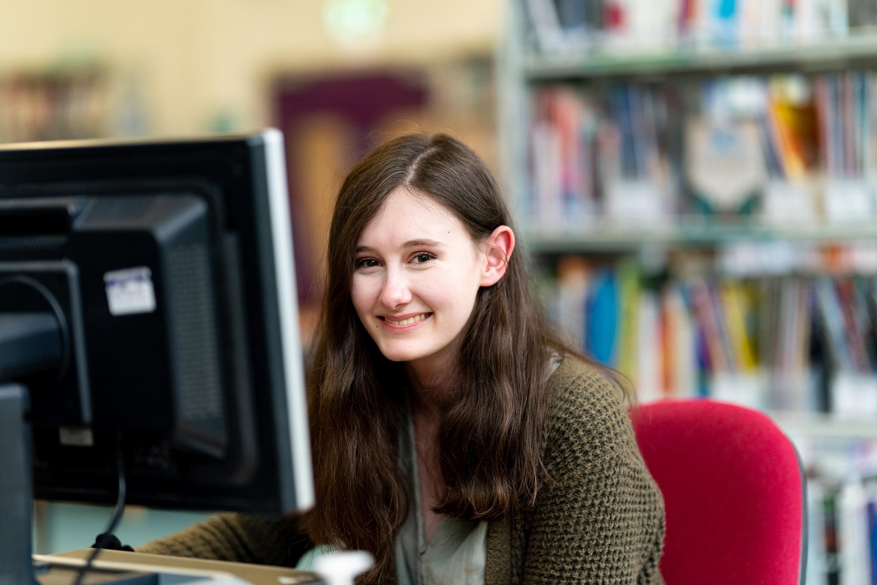 A student smiles at the camera as she sits in front of a computer sat in one of the college's study centres.