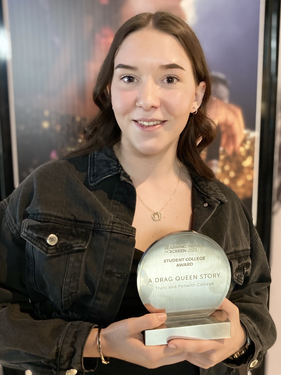 Arianne smiling while holding her trophy from the Learning on Screen awards. The trophy reads "Student College Award, A Drag Queen Story, Truro and Penwith College."