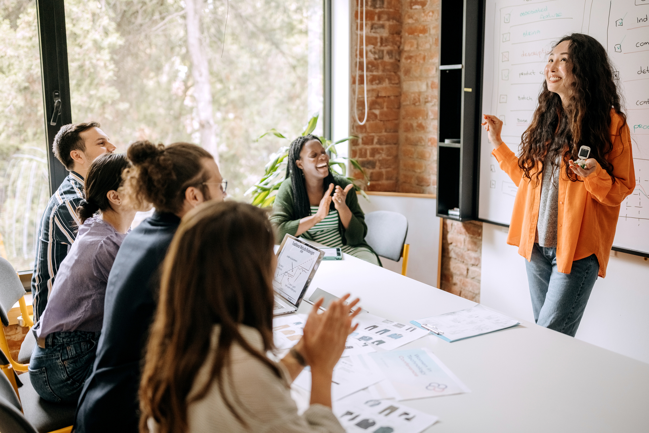 Young female entrepreneur presenting her small solar robot to her coworkers on a business meeting