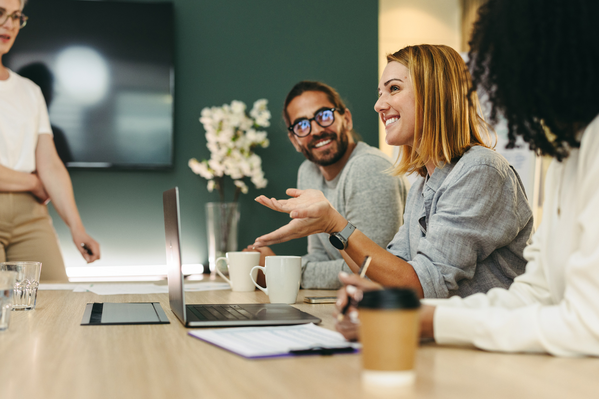 Business woman talking to her colleagues during a meeting in a boardroom. Group of happy business people working together in a creative office.