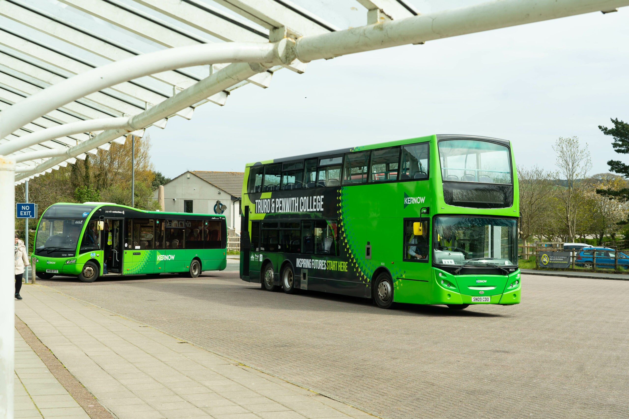 A green bus with Truro and Penwith College branding on the side of it sits in the bus bay at the College.