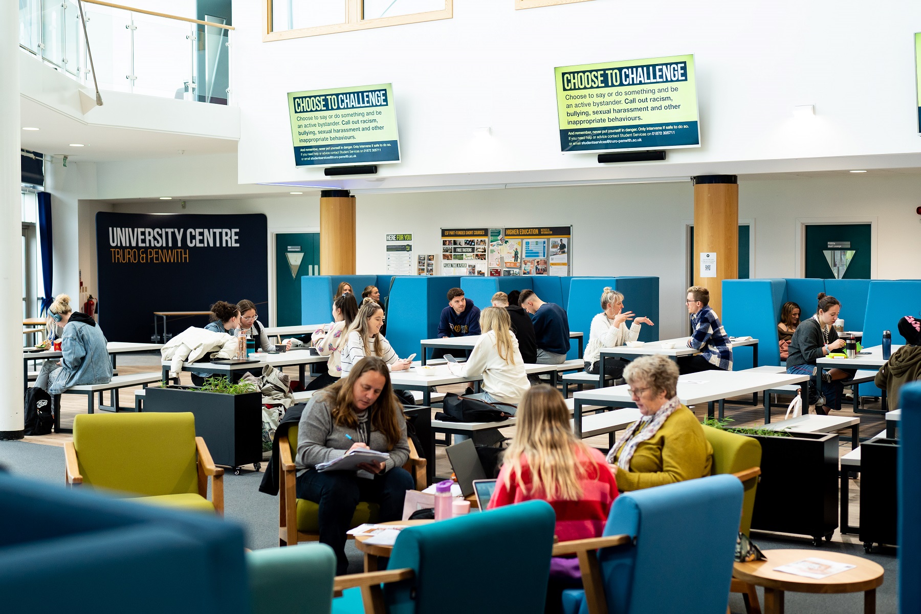 Lots of students sit in the Fal building refectory, meeting and chatting with friends or working quietly.