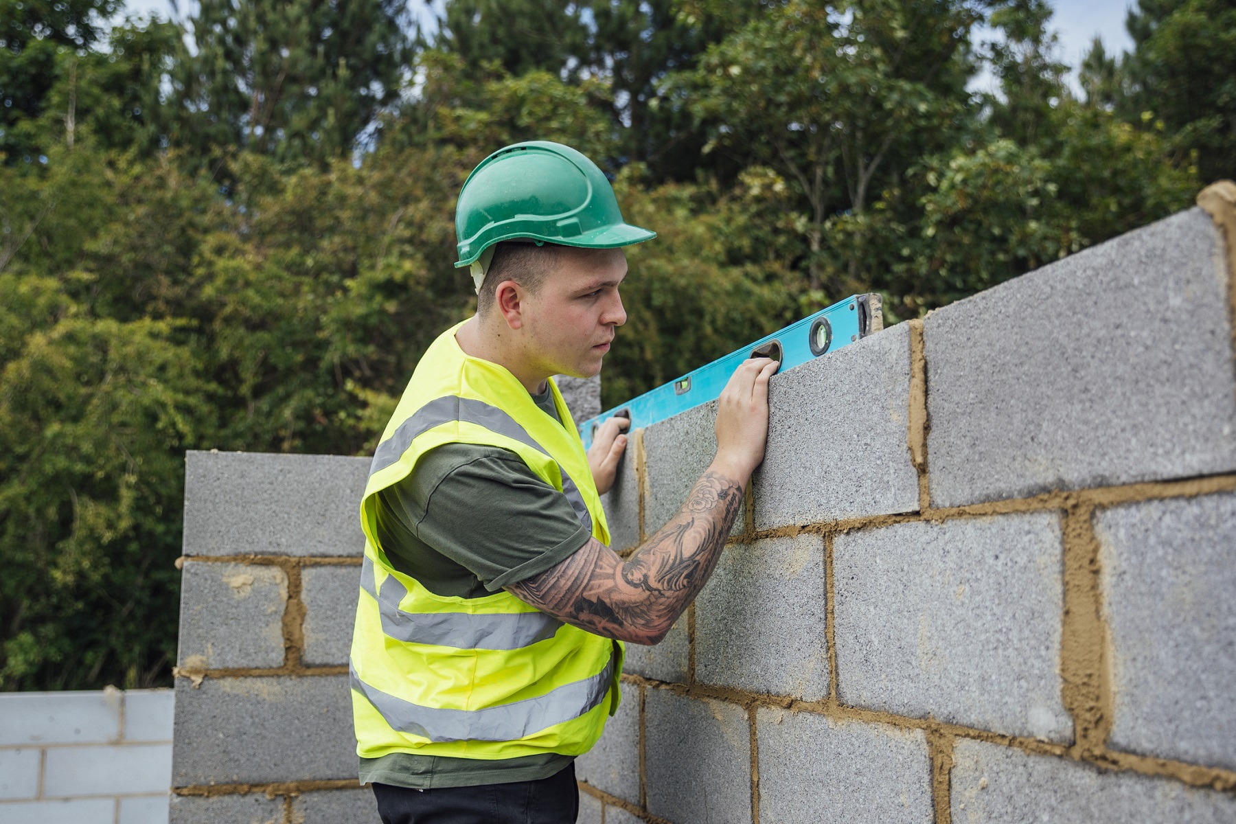 A shot of a spirit level being used to check some brickwork by a caucasian male construction worker.