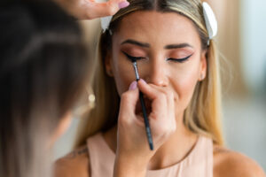 Close up of a makeup artist applying makeup on a model’s face in a studio before a photo shoot.