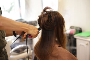 Male hairdresser ironing a woman's hair