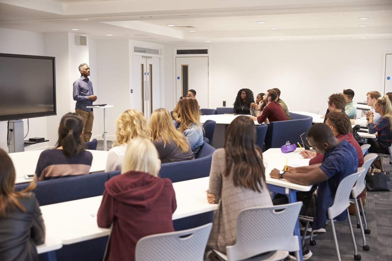 Students in a business related seminar listening to a male lecturer.