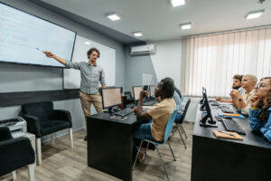 Young male teacher teaching young students a digital skills class in the classroom.