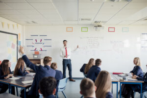 Teenage female student raising her hand to answer a question.