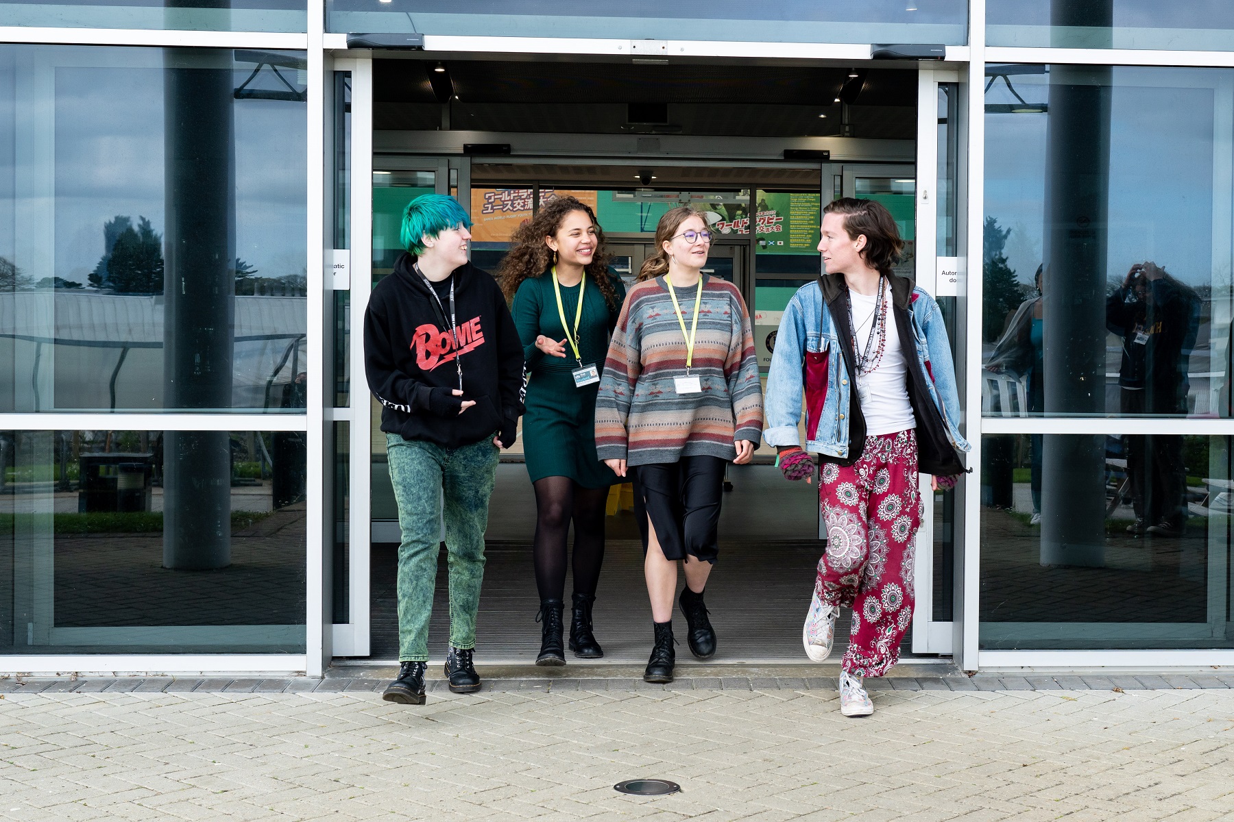 A group of students are exiting a building on Truro campus, chatting and laughing.