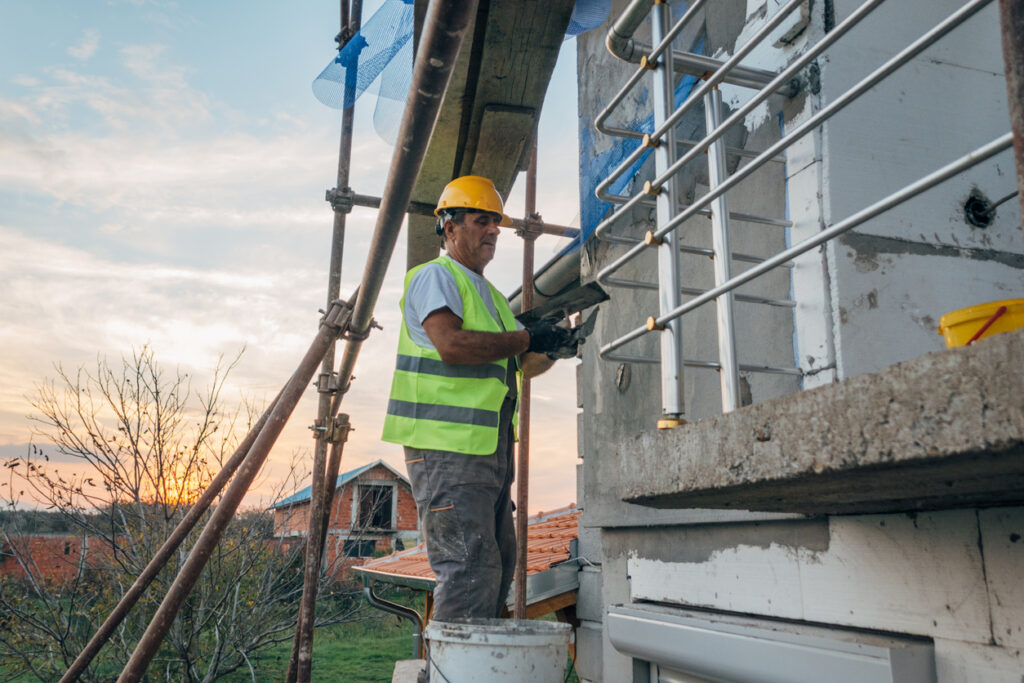 A construction worker builds the facade of a building
