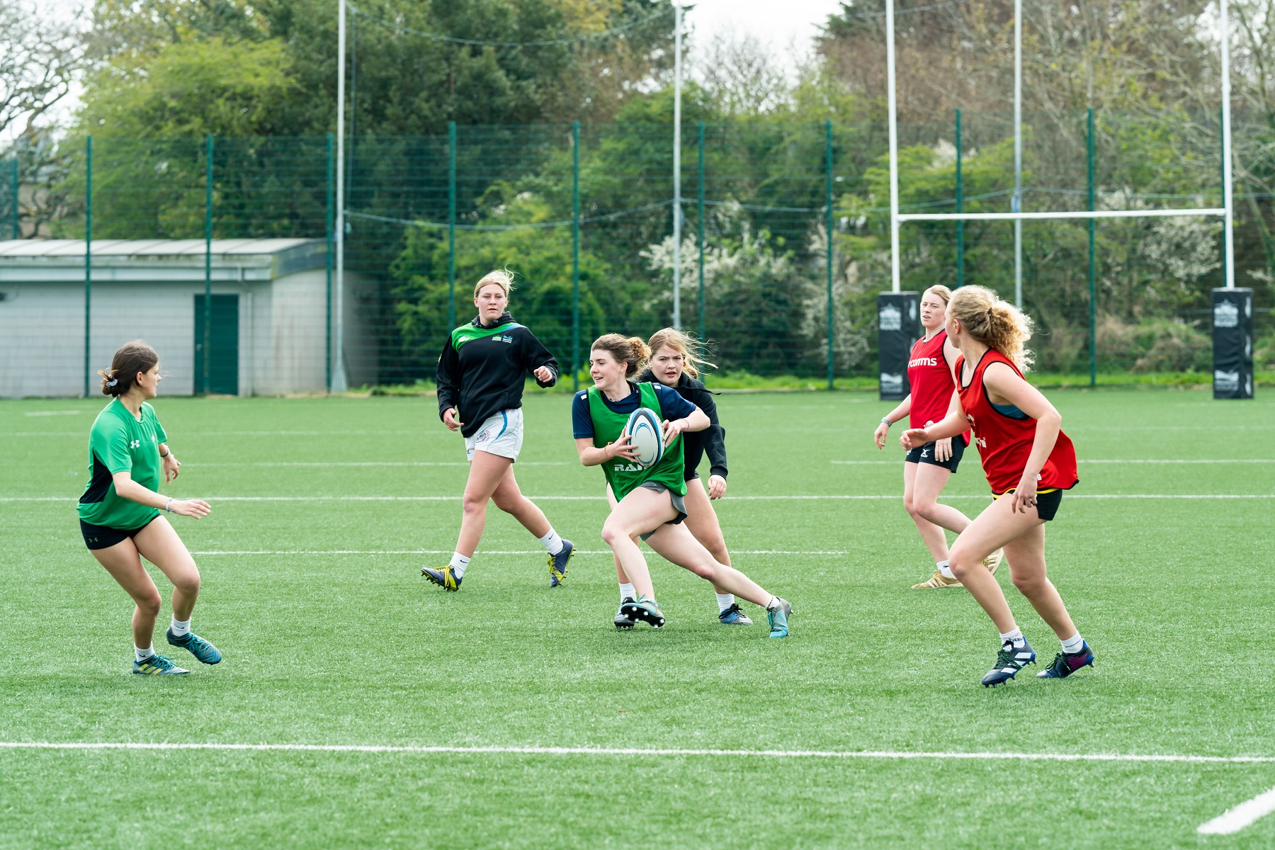 A team of female rugby players run on the AstroTurf.