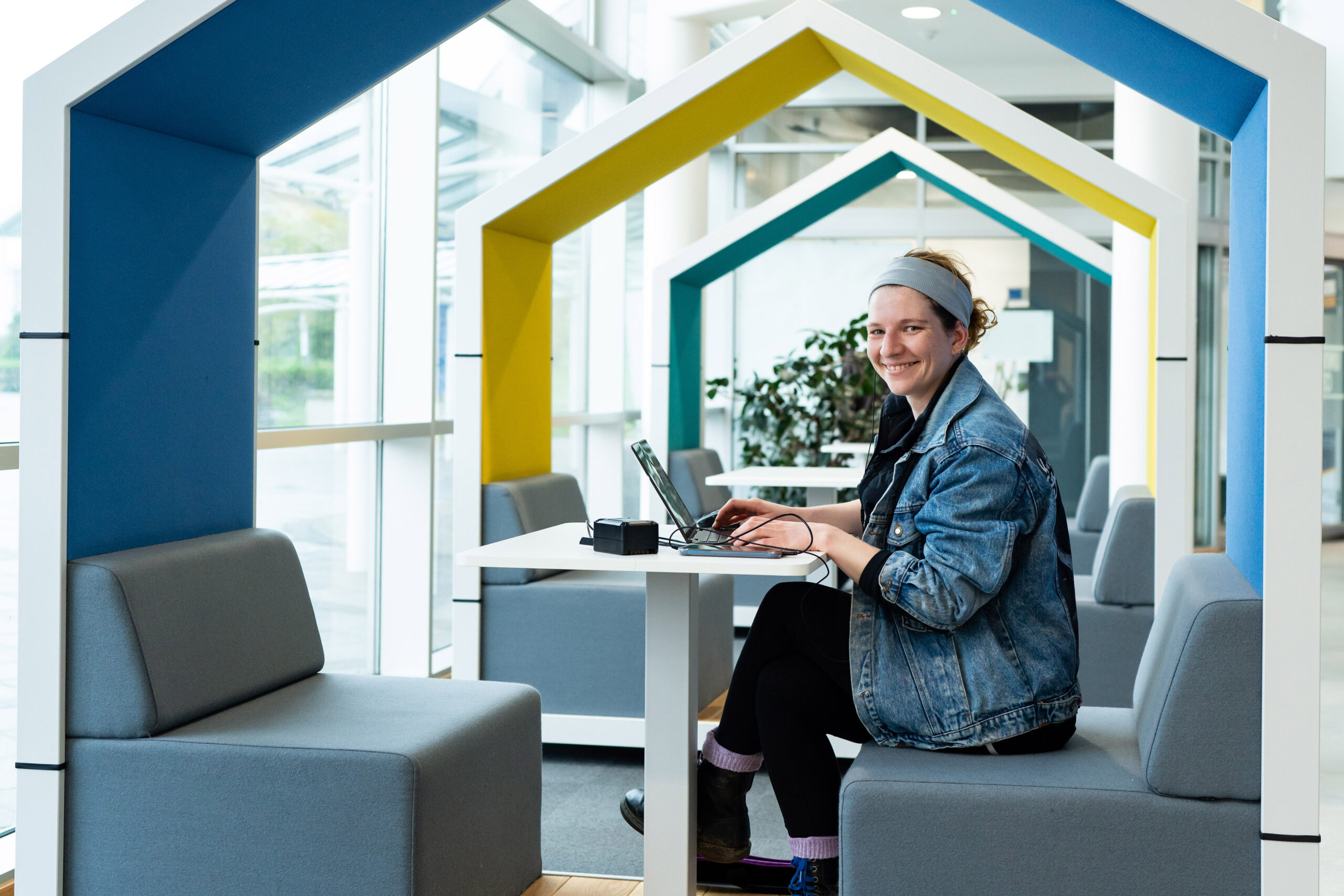 An adult student sits in a seating booth with a laptop working at the University Centre Truro and Penwith.