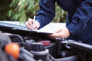 An unknown engine engineer is checking a car in blue overalls.