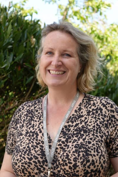 An image of Andrea smiling at the camera wearing a animal print top.