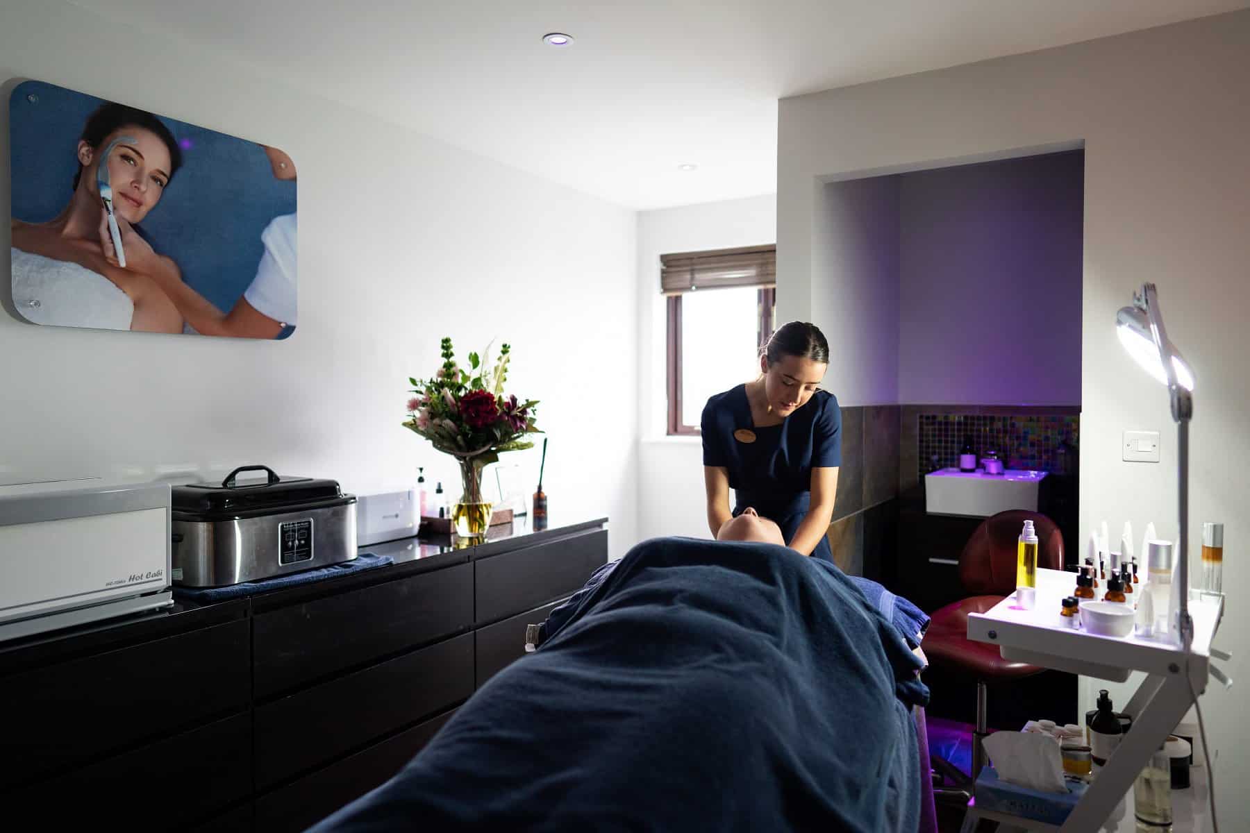 A spa therapist apprentice works on a client in a relaxing spa room.