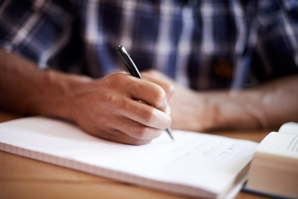 Closeup shot of a young student writing on a note pad