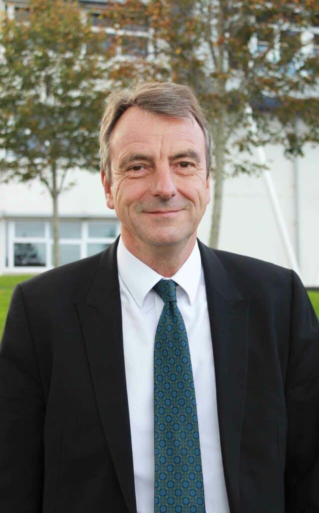 Robert Chair of Governors outside by the trees smiling at the camera.