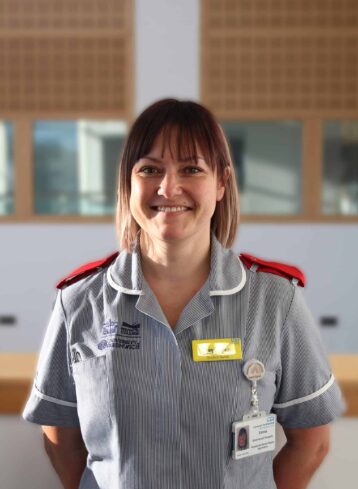 Student Emma stands in her Nurse's uniform with her hands behind her back.