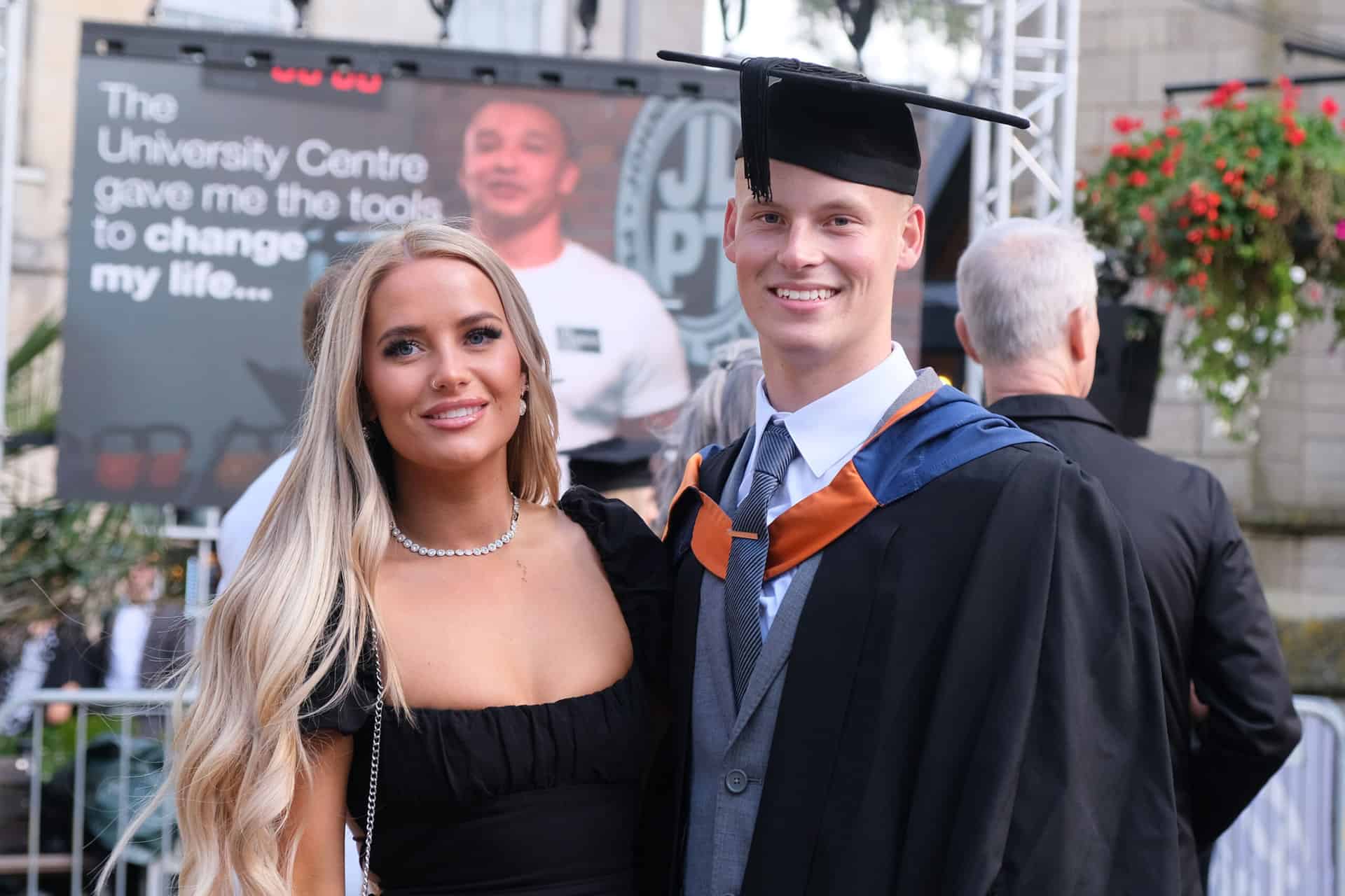 The University Centre Truro & Penwith Graduation 2023. A graduate stands outside smiling with his guest.