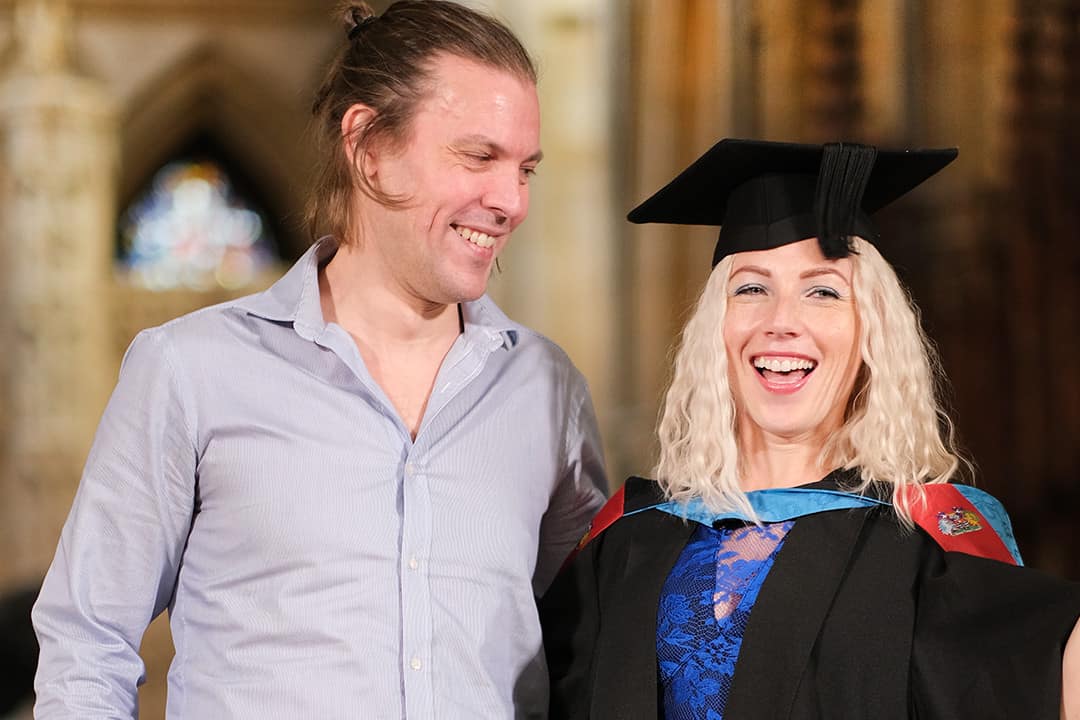 Graduate 4.2 University Centre Truro & Penwith Graduation 2023. A graduate stands smiling with a guest.