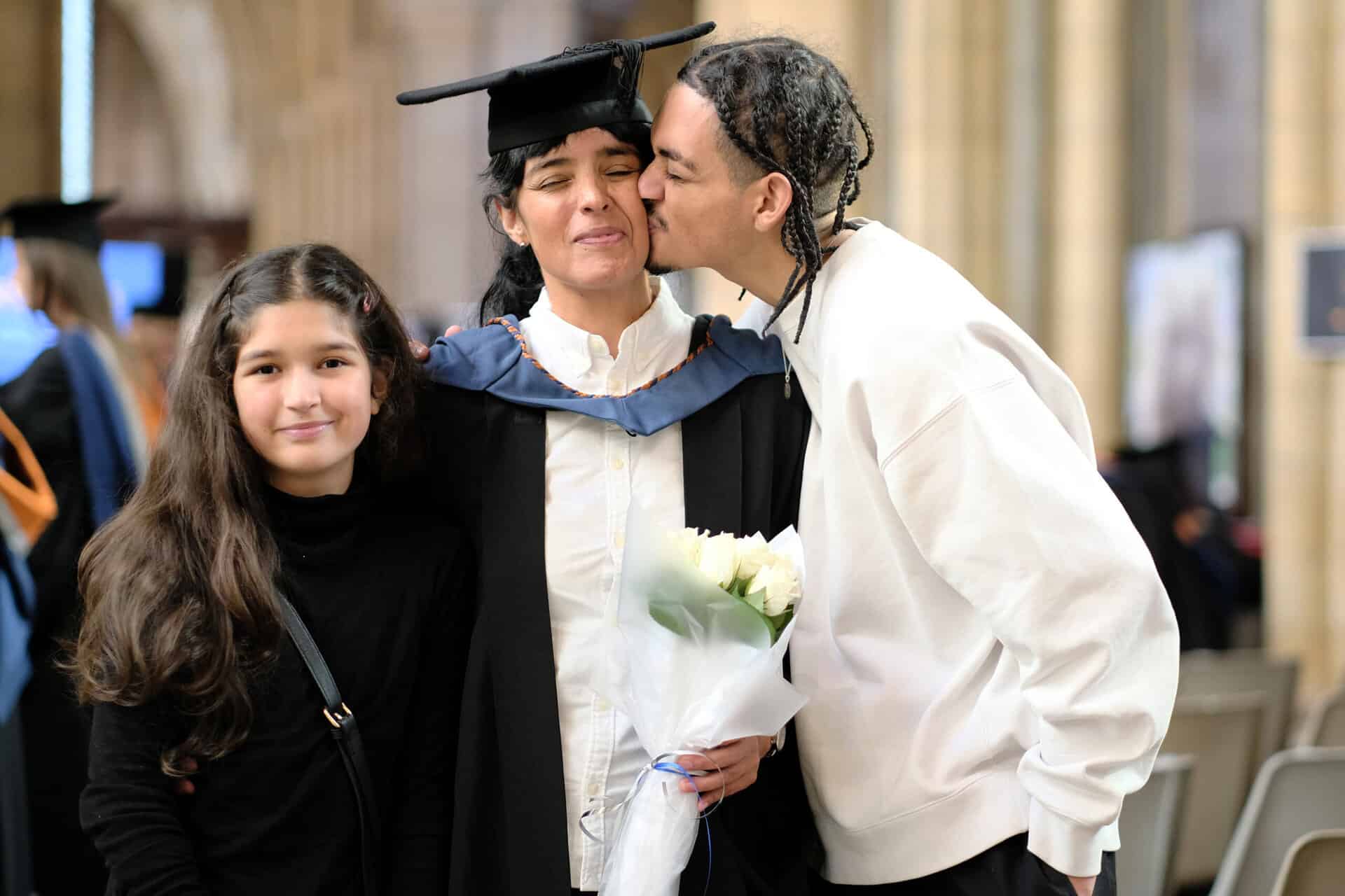 The University Centre Truro & Penwith Graduation 2023. Image of a family with guest kissing the graduate's cheek.