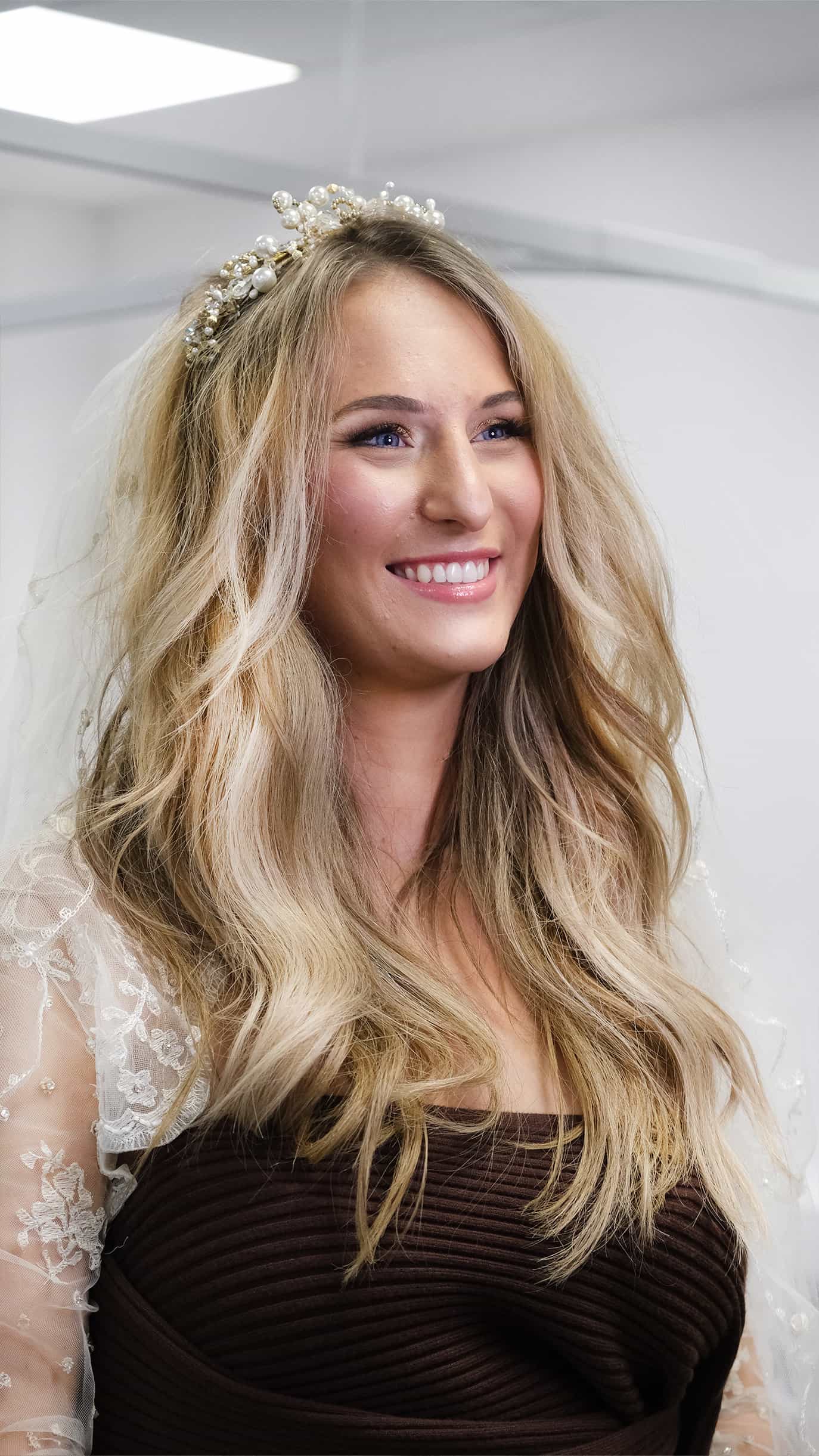 A model with long blonde hair wearing a tiara with a full face of makeup. Hair and Beauty enrichment