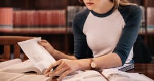 Close up of young woman reading book in the library.
