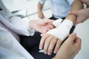 The doctor wraps a bandage on the arm of the injured patient.