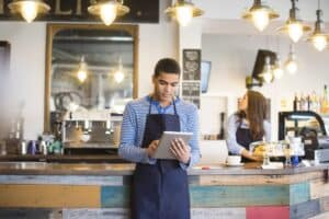 Two young baristas using a digital tablet by the bar area.